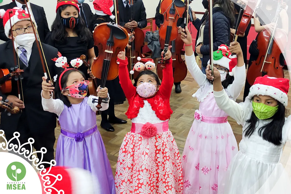 Niñas con vestidos de fiesta sostienen sus arcos entre los músicos de la orquesta