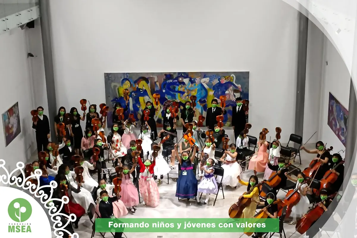 Orquesta infantil de MSEA reunida en una sala, con niños y jóvenes sosteniendo violines y violonchelos